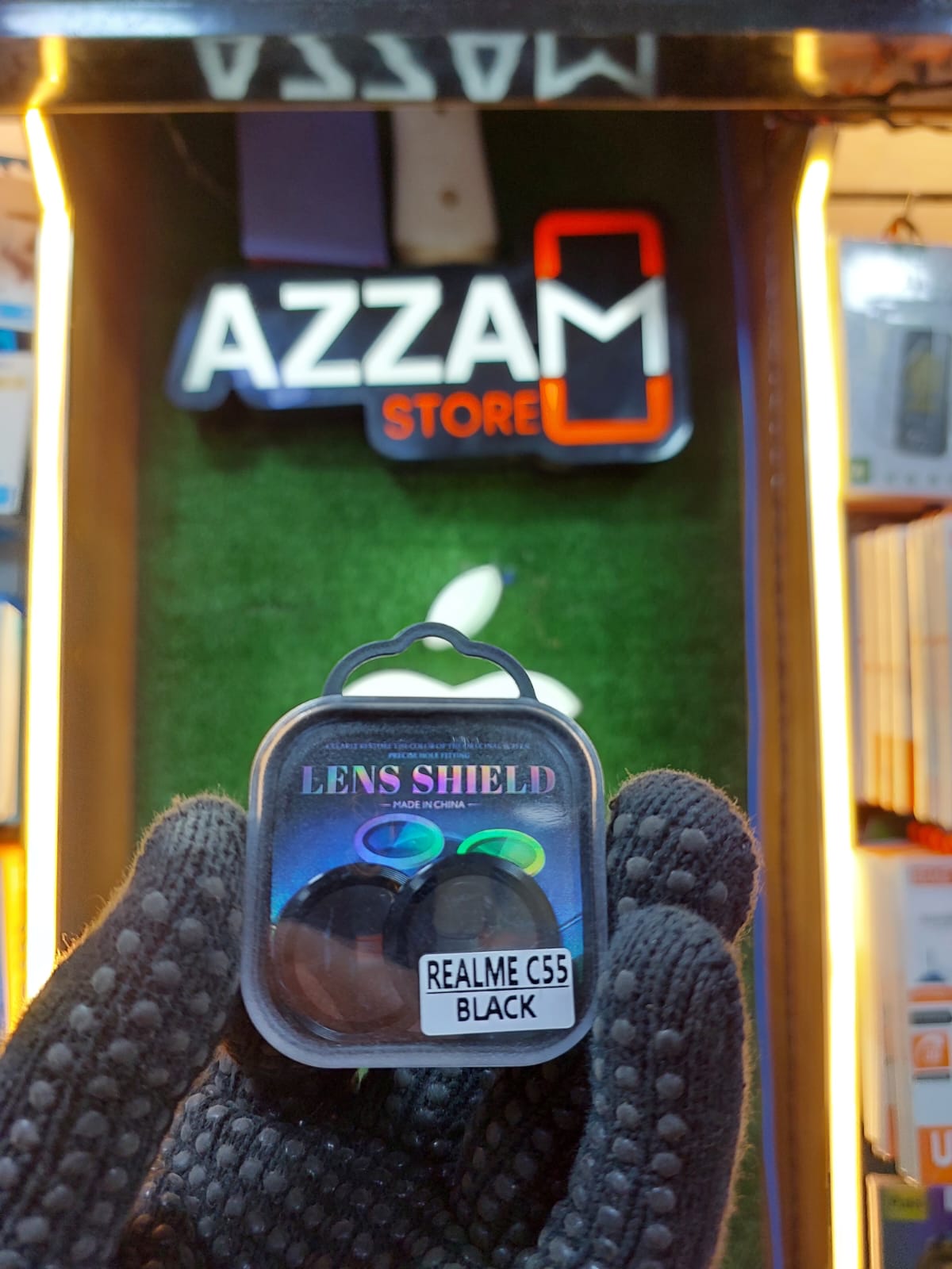 Lens shield packaging held in front of an Azzam Store sign